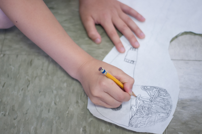 A student meticulously works on a drawing of a human brain.